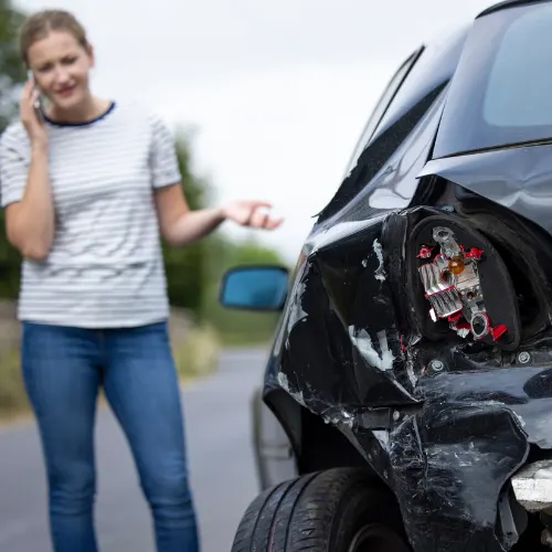 Unhappy Female Driver With Damaged Car After Accident Calling Insurance Company On Mobile Phone