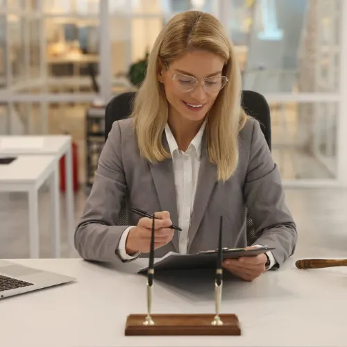 Smiling lawyer with clipboard working at table in office